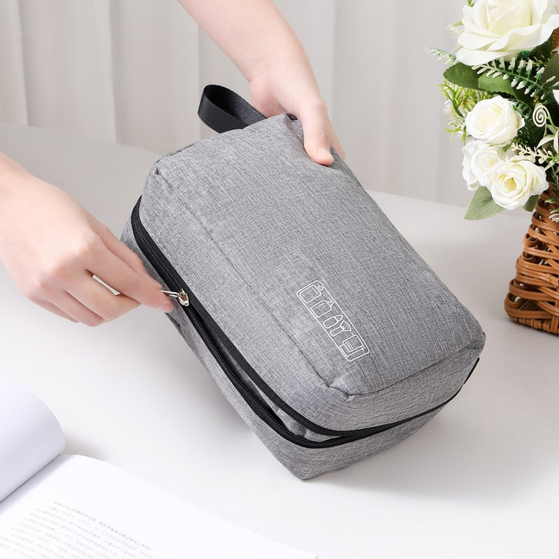 Gray toiletry bag with black zipper being held by a hand